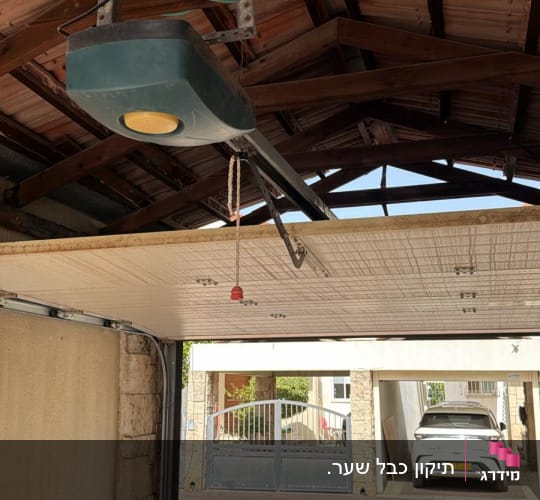מנגנון שער חשמלי בתוך חניה עם רכב